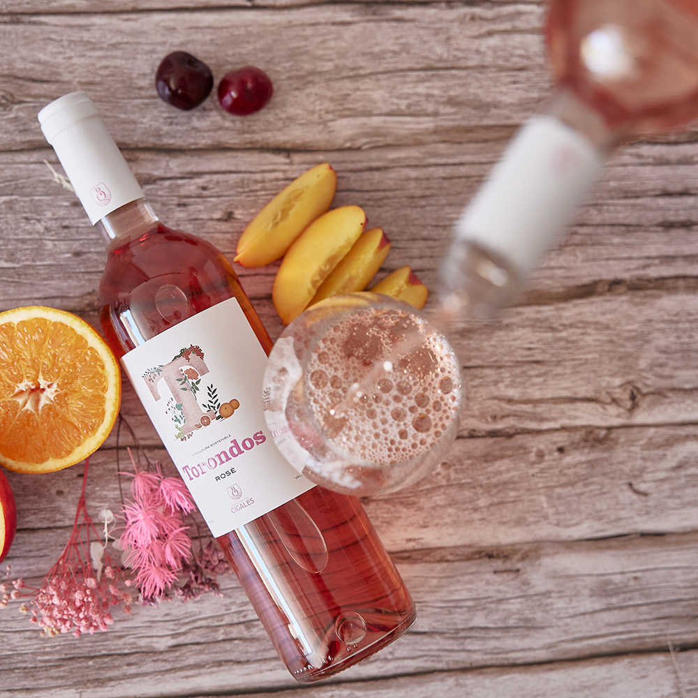 Botella Torondos Rosé en una mesa con una copa de vino y frutas.
