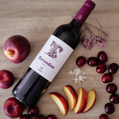 Botella Torondos Tinto en una mesa con frutas.