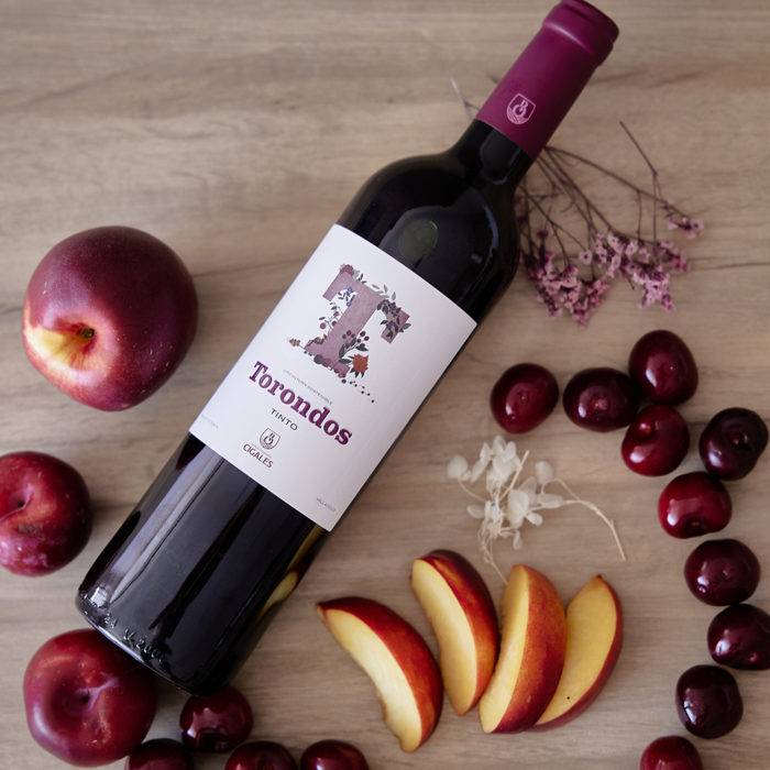 Botella Torondos Tinto en una mesa con frutas.